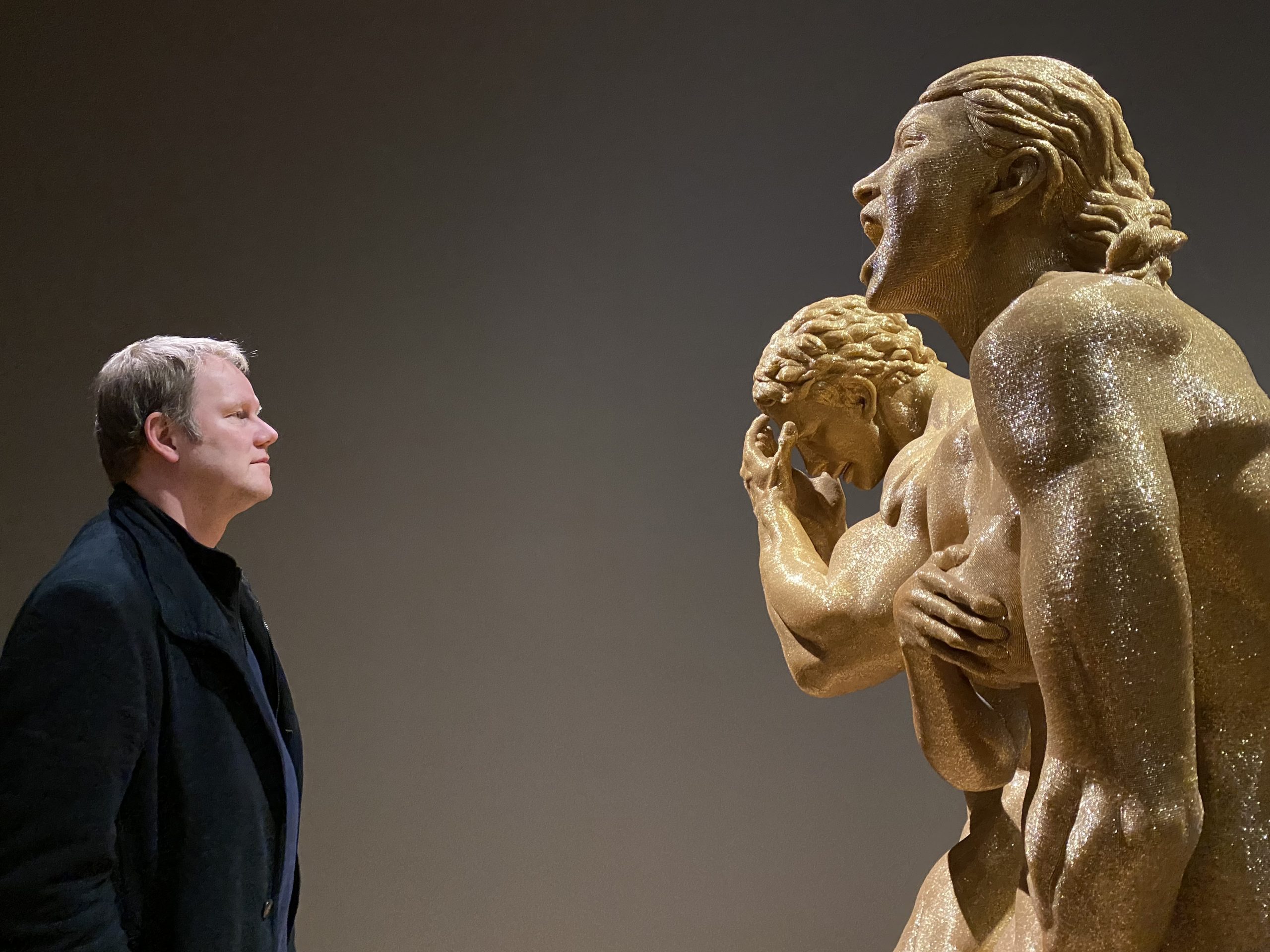 Armin Schobloch steht im Museum einer goldenen Skulpturengruppe gegenüber